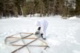 man setting down triangular frames on an snowy landscape