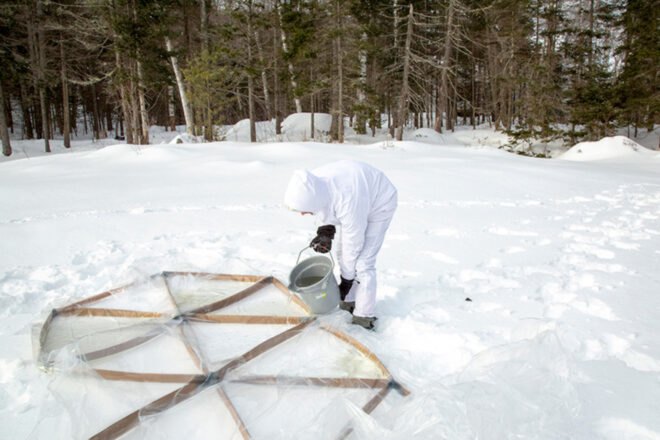 man setting down triangular frames on an snowy landscape