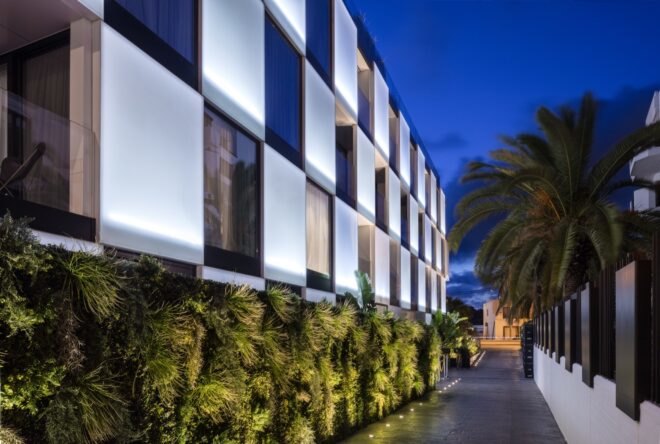 hotel with green wall below and white and glass checkered facade