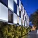 hotel with green wall below and white and glass checkered facade
