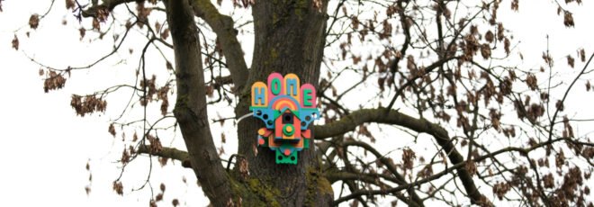 a colorful birdhouse tacked to a tree
