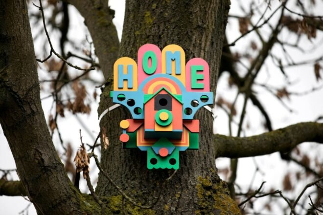 a colorful birdhouse tacked to a tree