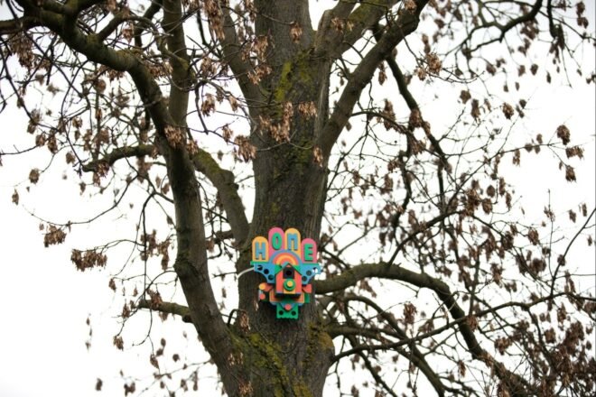 a colorful birdhouse tacked to a tree