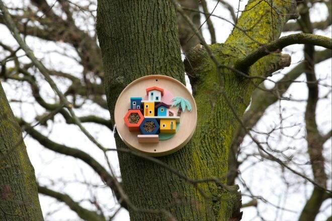 a colorful birdhouse tacked to a tree