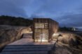 home wrapped in timber slats on concrete base all lit up at night