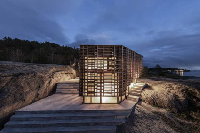 home wrapped in timber slats on concrete base all lit up at night