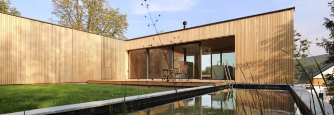 timber home lined with grass and a nearby natural pool