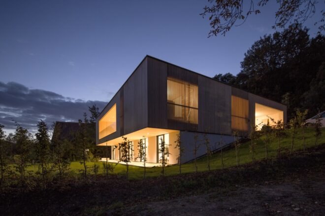 the home illuminated with lights in the evening
