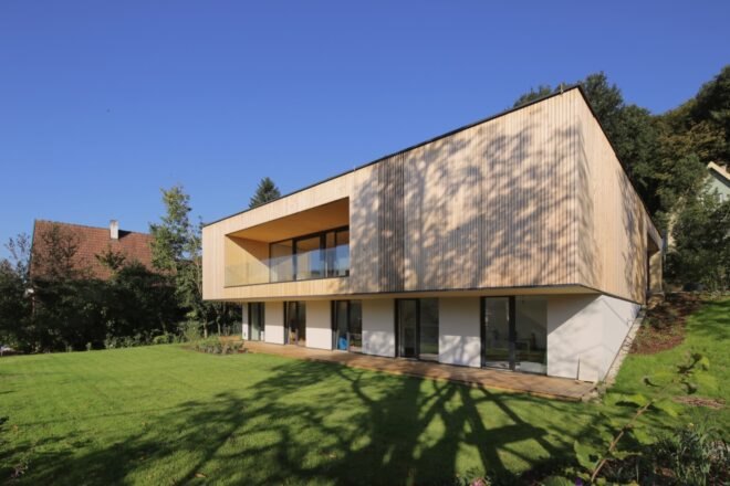 timber home lined with grass and a nearby pond