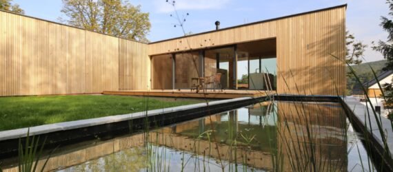 timber home lined with grass and a nearby natural pool