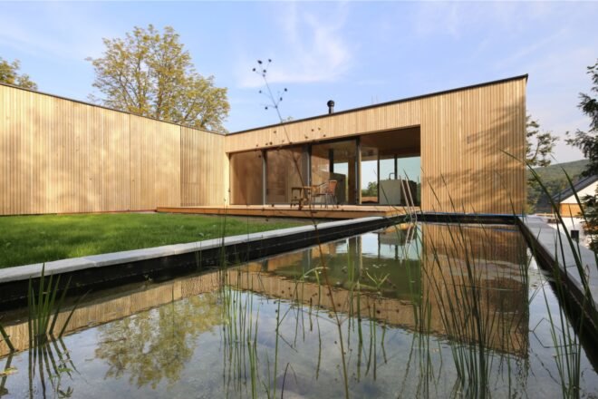 timber home lined with grass and a nearby natural pool