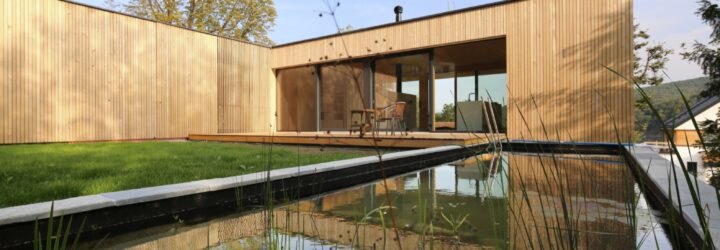 timber home lined with grass and a nearby natural pool