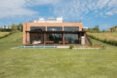 brick home with three large glass facades looking out over grassy landscape