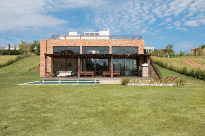 brick home with three large glass facades looking out over grassy landscape
