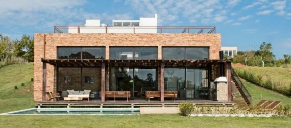 brick home with three large glass facades looking out over swimming pool