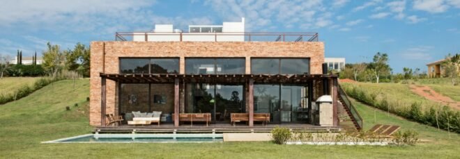 brick home with three large glass facades looking out over swimming pool