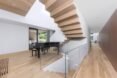 white living space with wood staircases and black piano