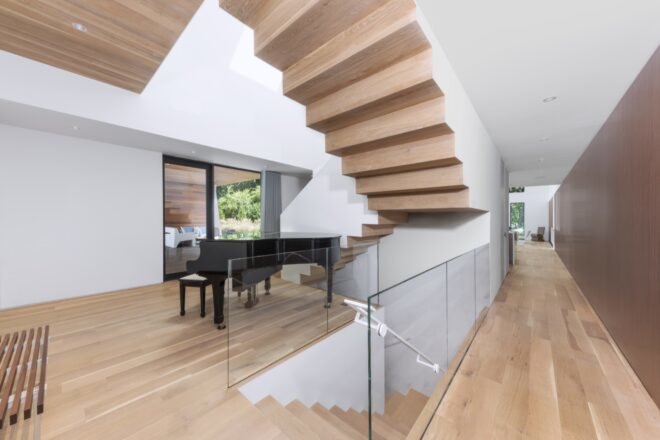 white living space with wood staircases and black piano
