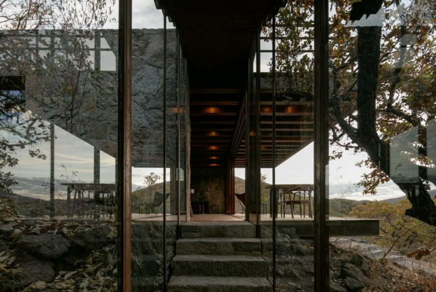 glass-enclosed walkway leading up to stone cabin
