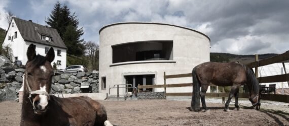 white round building behind fenced area with horses