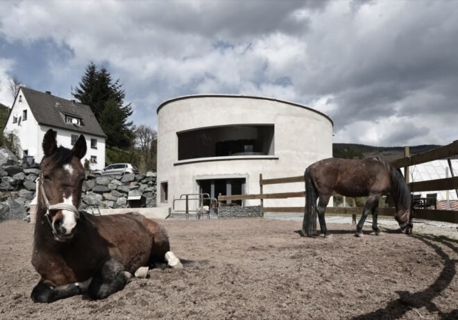 white round building behind fenced area with horses