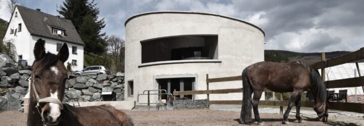 white round building behind fenced area with horses