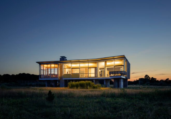 modern home with glass facade sitting over green landscape