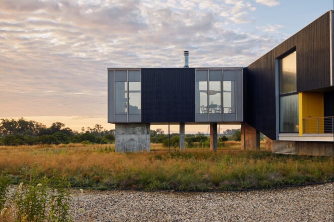 modern home sitting on concrete stilts above the landscape