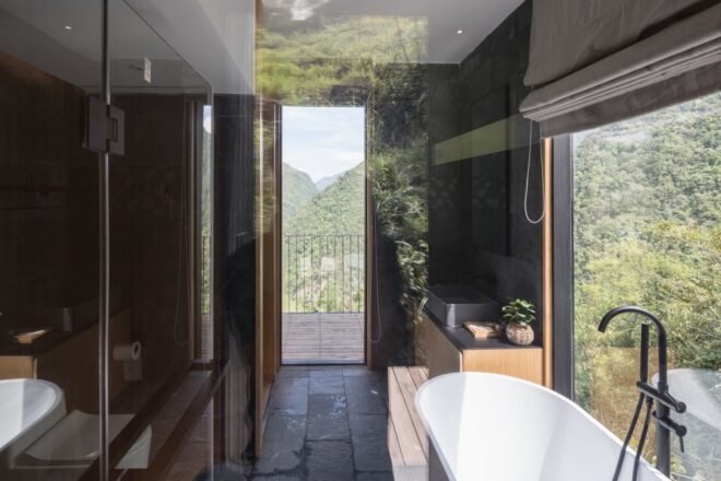 black bathroom with freestanding tub and door leading to outdoor deck