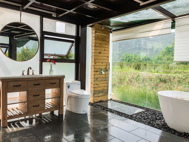 toilet and free-standing bathtub in room with glass walls