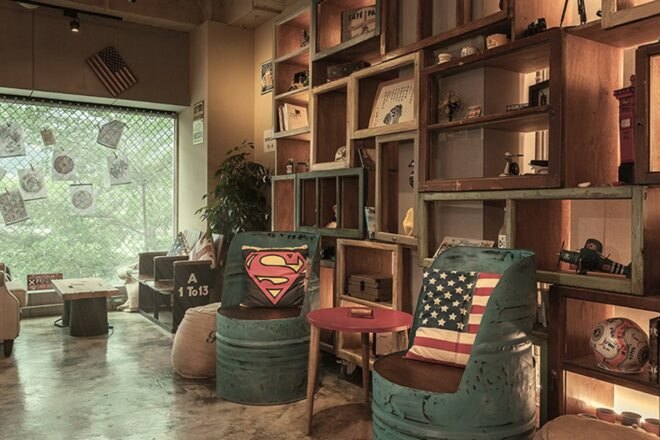 two seats made of metal barrels against a tall shelving system made from old window frames