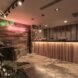 wooden reception desk and wood wall with neon sign that reads Wow Hostel