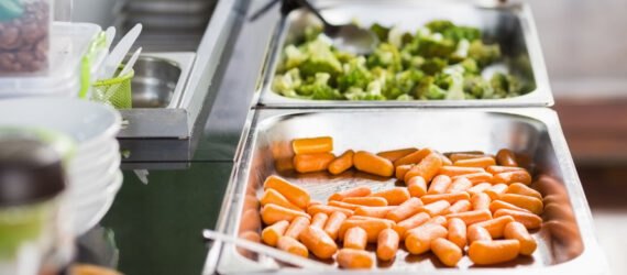 cafeteria with trays of carrots and broccoli