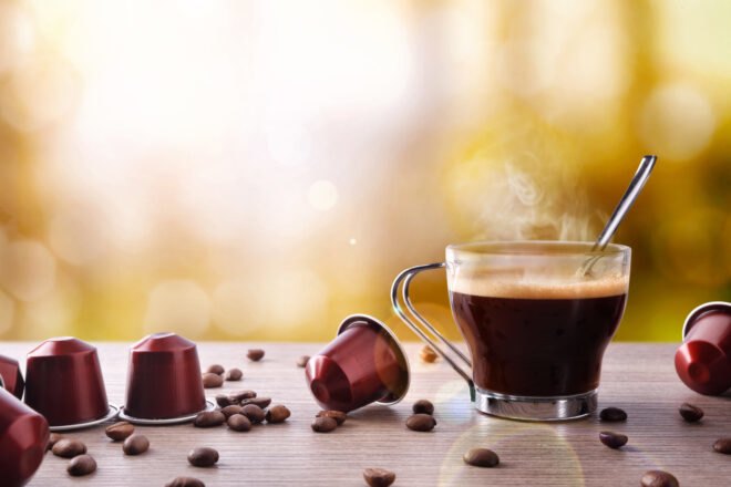 coffee pods and beans next to cup of coffee on a table