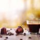 coffee pods and beans next to cup of coffee on a table