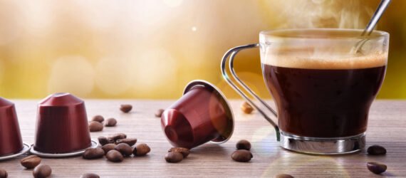 coffee pods and beans next to cup of coffee on a table