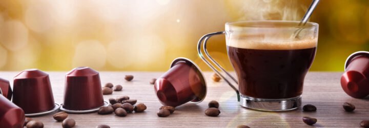 coffee pods and beans next to cup of coffee on a table
