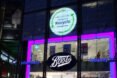 storefront lit up at night with acuvue contact recycling sign