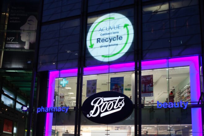 storefront lit up at night with acuvue contact recycling sign