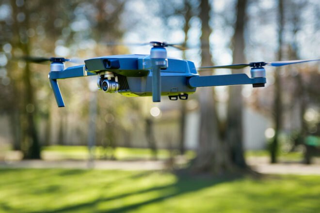 drone flying in a park filled with trees