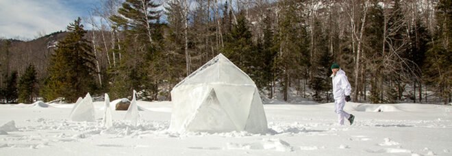 man walking toward geodesic ice igloo