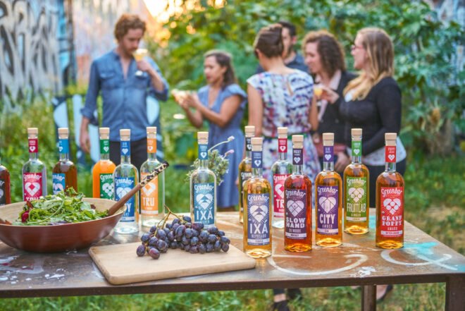 bottles of alcohol on table in foreground with people chatting in background