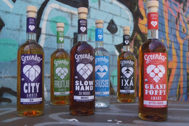 bottles of alcohol with colorful labels in front of a colorful wall