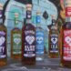 bottles of alcohol with colorful labels in front of a colorful wall