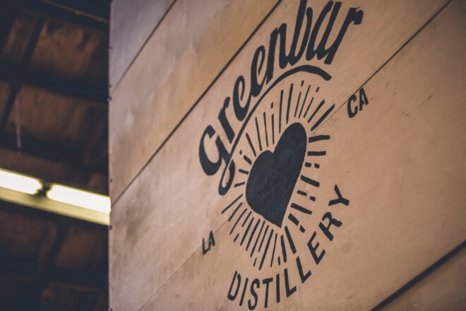 wood sign that reads "Greenbar Distillery"