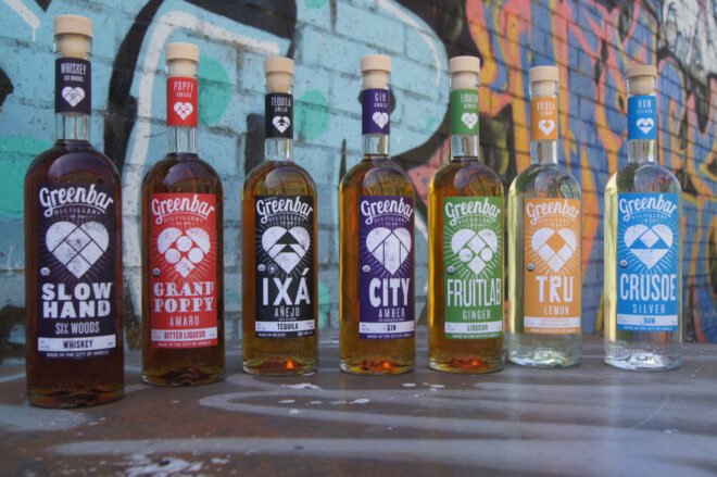 bottles of alcohol with colorful labels in front of a colorful wall