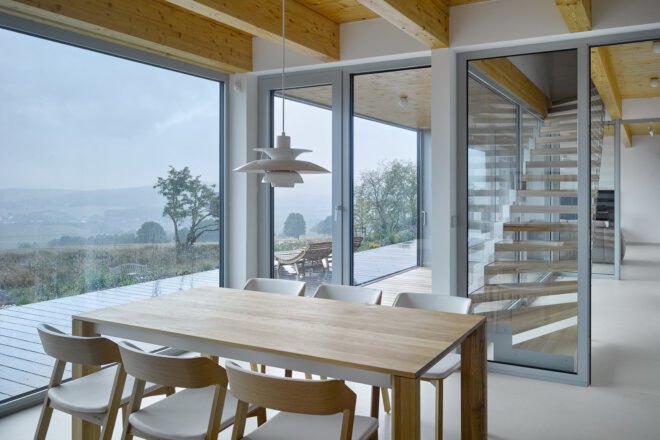 interior of home with wooden table and chairs and wood ceiling with glass doors leading towards wooden staircase