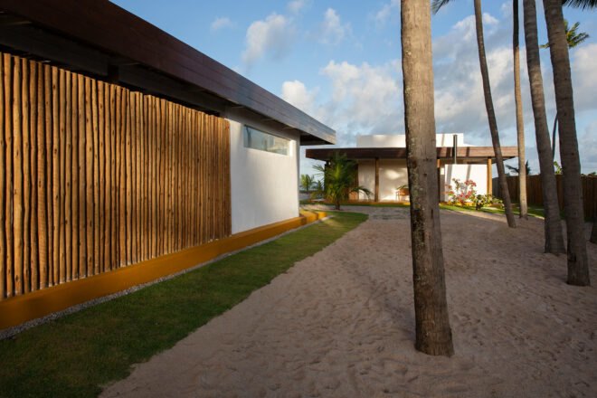 exterior of beach house with exposed twigs near palm trees and sand