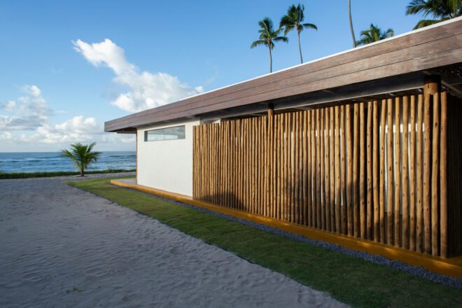 exterior of beach house with exposed twigs near palm trees and sand