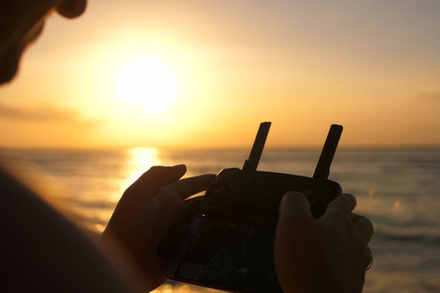 person holding drone controls at beach during sunset